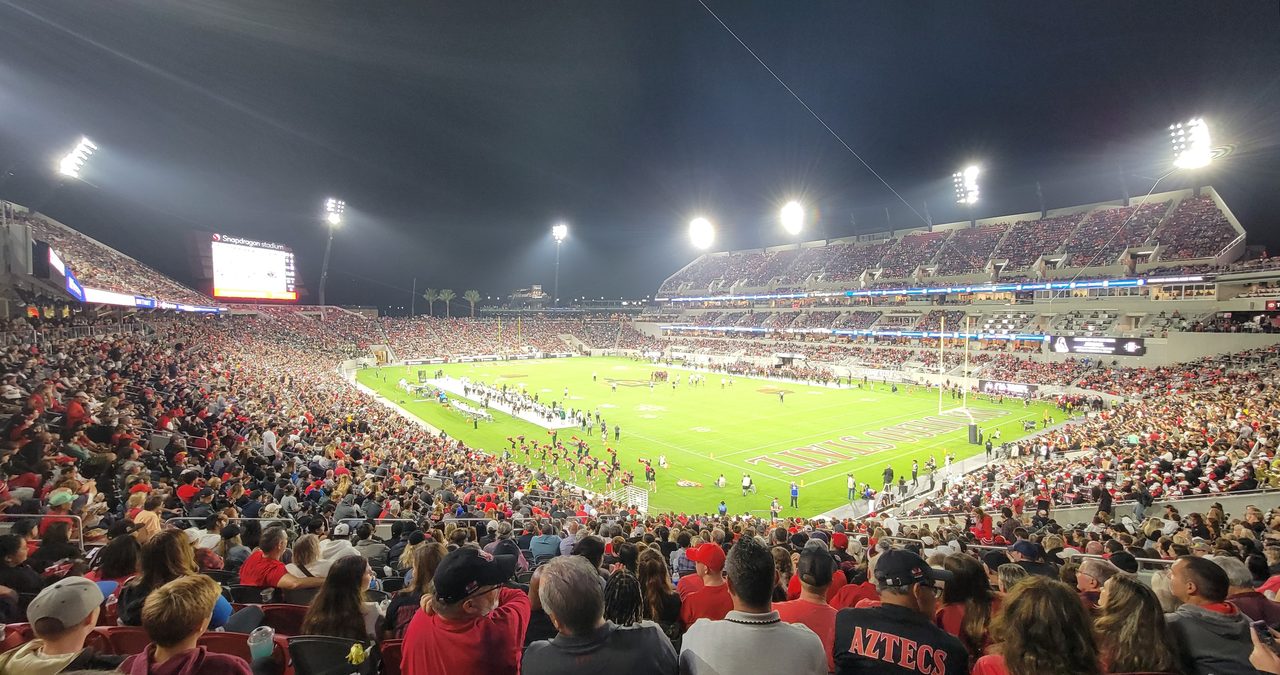 Football stadium at night under floodlights packed with fans