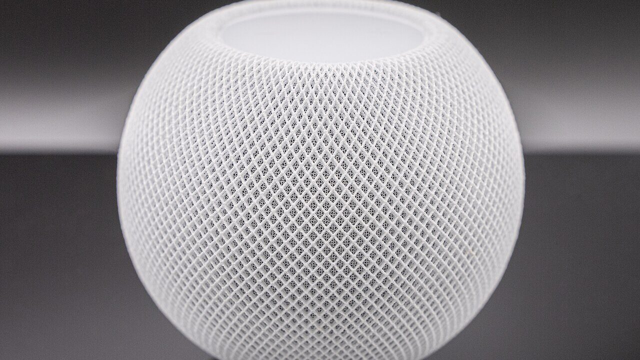 White Apple HomePod mini smart speaker on dark background