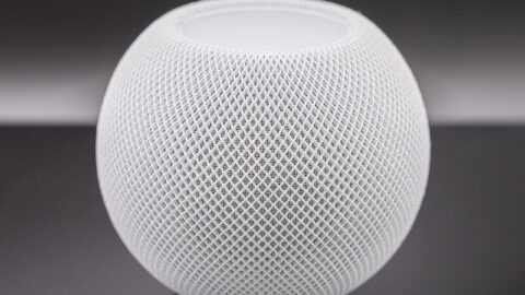 White Apple HomePod mini smart speaker on dark background