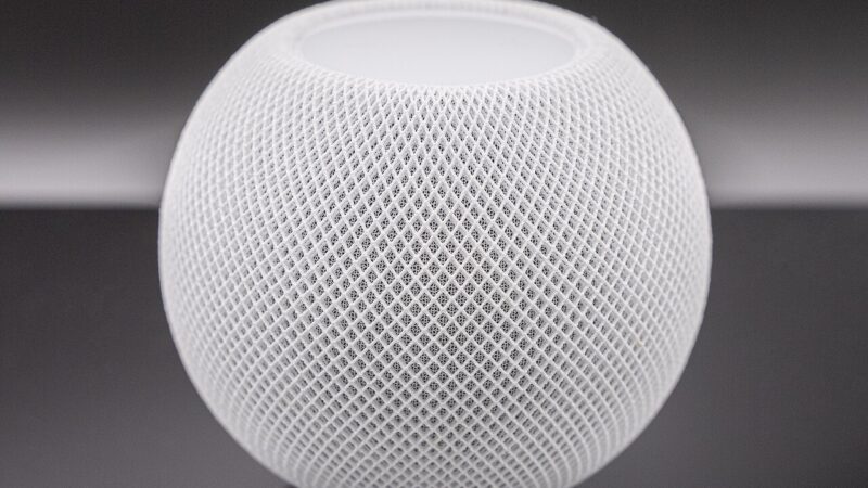 White Apple HomePod mini smart speaker on dark background